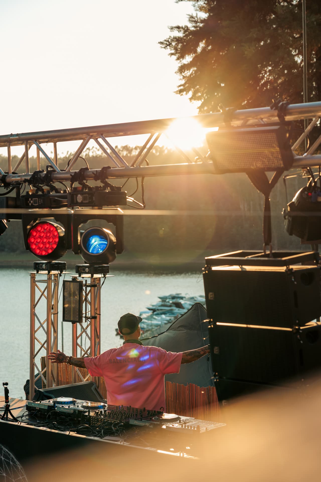 DJ with arms raised as the sun lowers