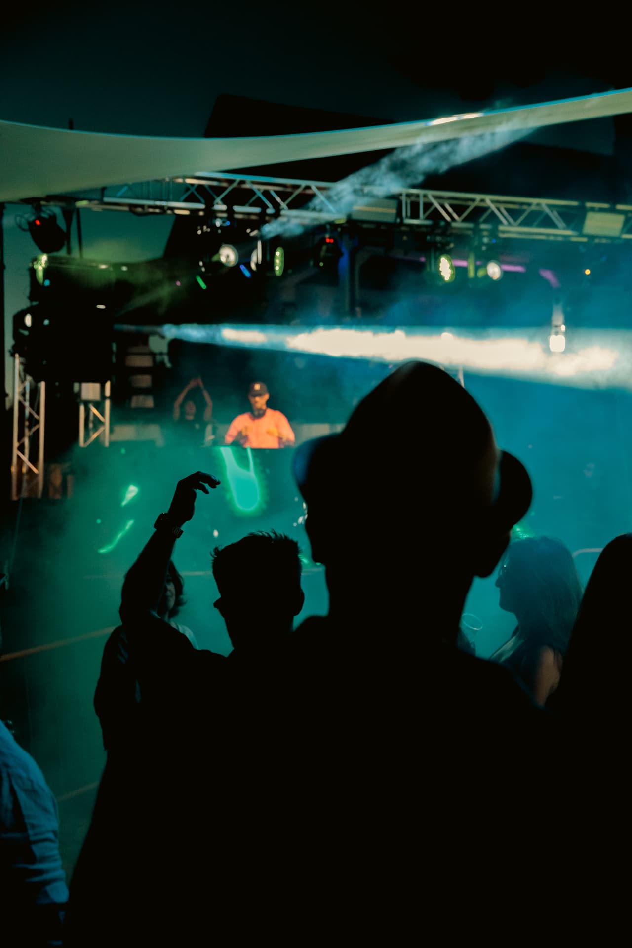 Silhouettes with hands raised in teal haze